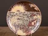 a plate with a painting on it sitting on a table