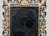 un cadre doré richement décoré, avec un miroir noir au centre