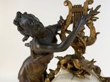 a clock with a statue of a woman holding a harp