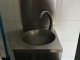 un lavabo en acier inoxydable dans des toilettes publiques, équipé d'un tuyau bleu
