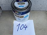 a can of paint sitting on top of a cement floor next to a sign