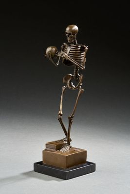 statue en bronze représentant un squelette tenant un crâne, posée sur un socle en bois