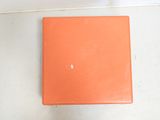 an orange box sitting on the floor next to a white wall