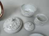 a white table with a bowl, cups, and a bowl on it