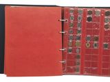 an open red book with a bunch of coins inside of it
