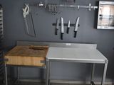 une cuisine équipée d'un évier, d'une planche à découper et d'autres ustensiles de cuisine accrochés au mur