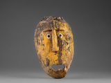 un masque en bois représentant un visage jaune sur fond gris
