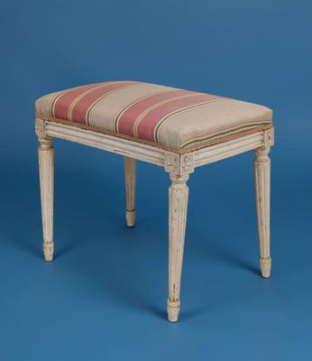 un repose-pieds rembourré dont l'assise est recouverte d'un tissu rayé