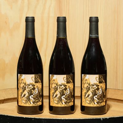 three bottles of wine sitting on top of a wooden barrel
