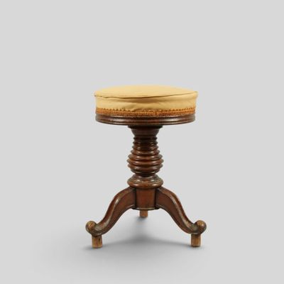 un petit tabouret en bois surmonté d'un coussin jaune