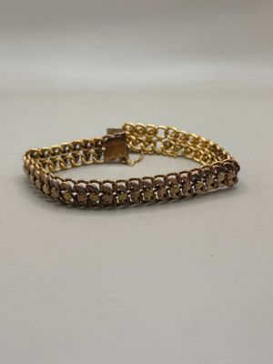 a close up of a gold chain bracelet on a white surface
