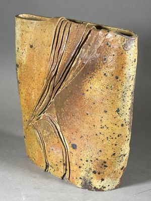 un vase marron orné d'un motif sur un fond gris