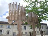 a wooden sculpture of a bird on a pole in front of a building