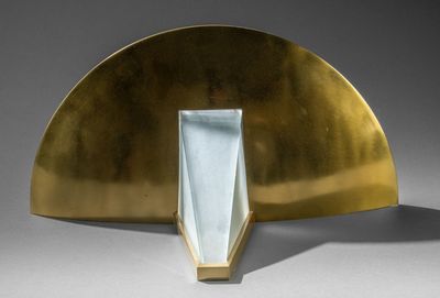 une image représentant une sculpture d'un éventail doré posé sur une surface grise