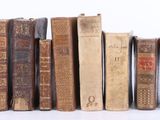 plusieurs vieux livres sont alignés sur une surface blanche