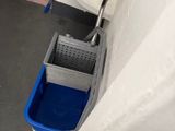 une serpillière et un seau dans un coin de la salle de bains