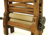an old wooden machine that has a roll of paper on it