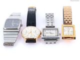 several watches are lined up in a row on a white surface