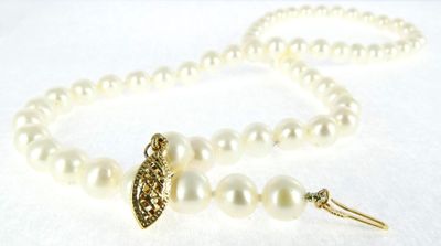 a close up of a white pearl necklace with a gold clasp