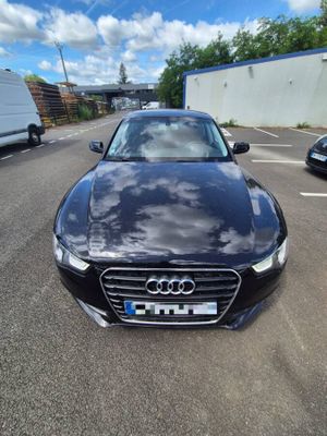 a black audi parked in a parking lot next to a white truck