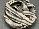 a silver brooch with a design on it on a table