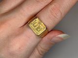 someone is holding a gold ring in their hand on a white surface