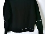 black jacket with zippers hanging on a hanger against a white wall