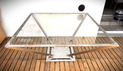 une table en verre avec un piètement en métal posée sur un parquet