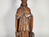une vieille statue en bois représentant un homme tenant un chien dans ses bras