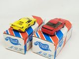 two toy cars sitting on top of boxes on a white surface