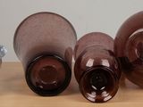 three brown glass vases sitting on top of a wooden table next to a glass
