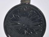 une bouteille en verre noir avec un bouchon noir posée sur une surface blanche
