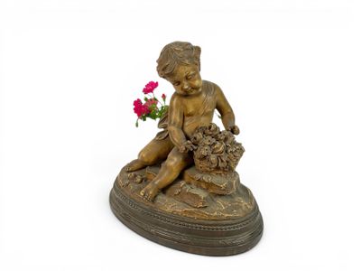 a statue of a boy sitting on a rock with a flower in his hand