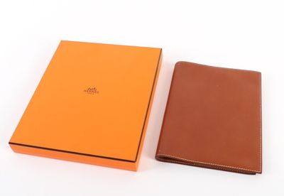 un portefeuille en cuir orange et marron à côté d'une boîte orange
