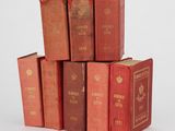 six livres rouges empilés les uns sur les autres sur une surface blanche