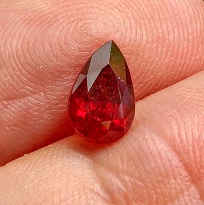 a red tear shaped diamond on a person ' s finger
