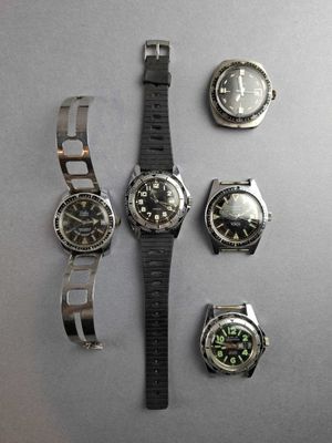 four watches and a watch bracelet on a table