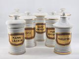 six white and gold canisters with labels on them on a white surface
