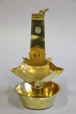 LAMPE A HUILE en laiton à décor incisé d'un visage dans un m…