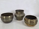three silver vases sitting next to each other on a white surface