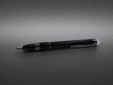 un stylo noir posé sur une table, devant un fond noir