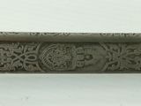 an old silver plate with a design on it on a white surface