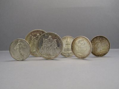 six different types of coins are arranged in a row on a white surface