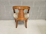 a wooden chair with a beige seat on a cement floor