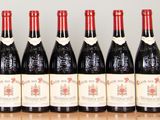 six bottles of red wine lined up on a wooden table