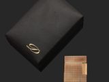 une boîte noire ornée d'un logo doré et d'un bracelet doré