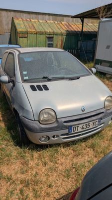 a small silver car parked in the grass next to a trailer