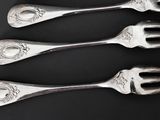 four silver spoons with ornate designs on them sit on a black surface