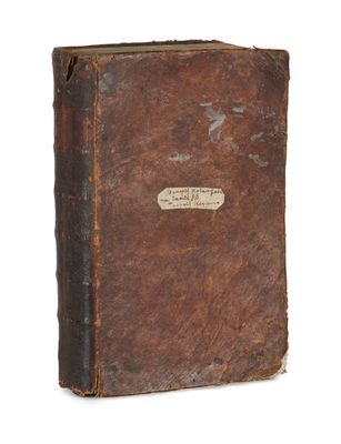 an old book with a brown cover sitting on top of a white surface