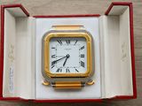 a gold and silver clock in a box on a table